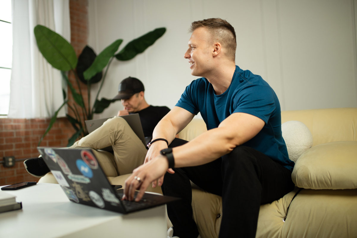 Landscape photo of Tim Welsh chatting with someone offscreen while sitting with other team members.